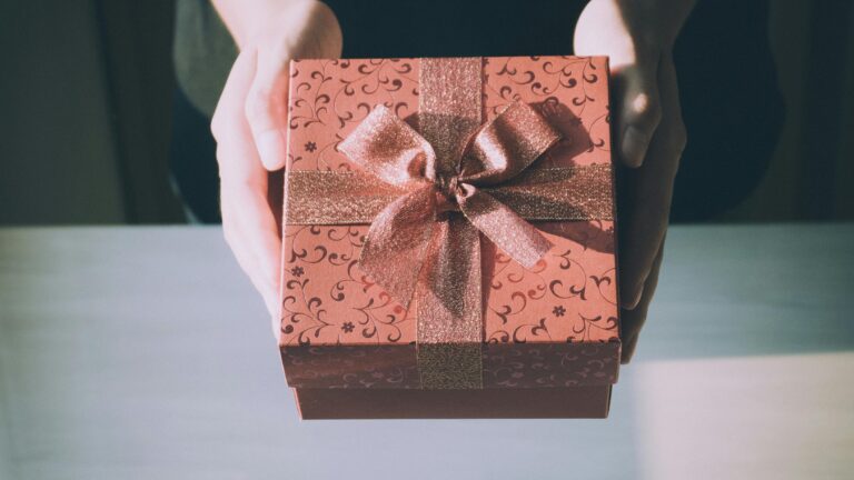 Hands presenting a beautifully wrapped gift box with a floral pattern, perfect for any celebration.